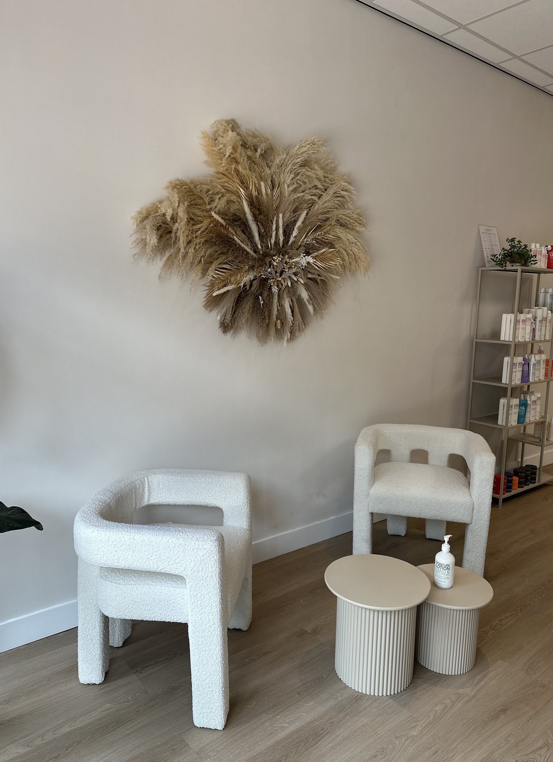 Zithoek in de salon met twee witte stoelen en pampas aan de muur