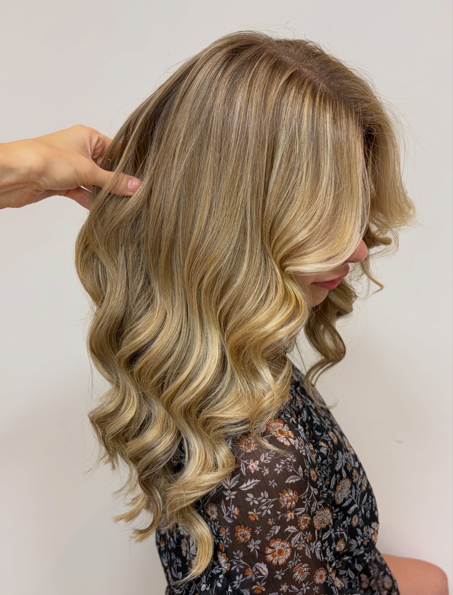 Blonde golven van opzij, met een hand die het haar optilt